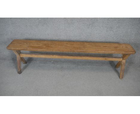 A vintage pitch pine bench on X framed stretchered supports. H.45 W.170 D.25cm 