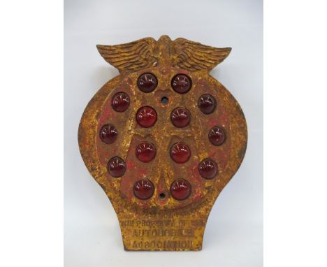 An AA cast iron plaque with ruby red reflectors. 