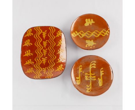 Group of three redware slip decorated stoneware ceramic pottery chargers. The two round chargers each with an incised signatu