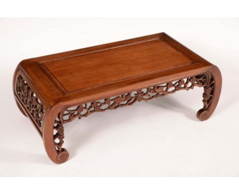 A Chinese hardwood low tea table, rectangular panel top, the shaped frieze and scroll ends pierced and carved with birds amon