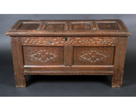 A Charles II oak blanket chest, hinged four panel top enclosing a till, the front carved with lozenges and leafy scrolls, sti