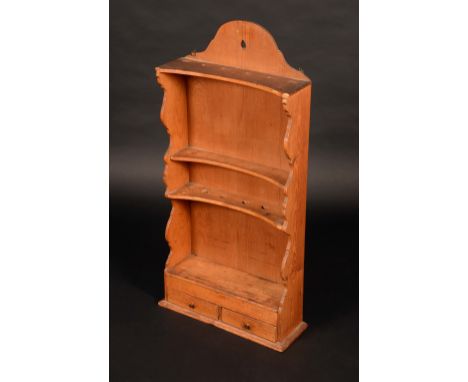 A 19th century pine concave fronted spoon rack, shaped cresting above two rows of apertures, a shelf and a niche, the base wi