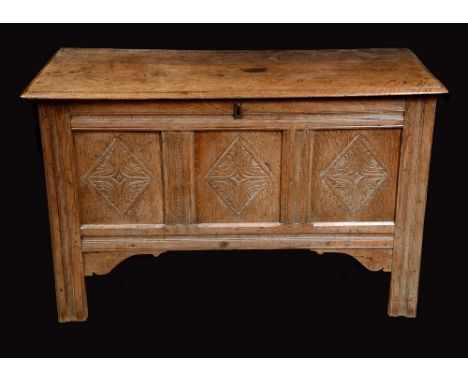 An early 18th century blanket chest, hinged moulded top, three panel front carved with lozenges, stile feet, V-shaped end pla
