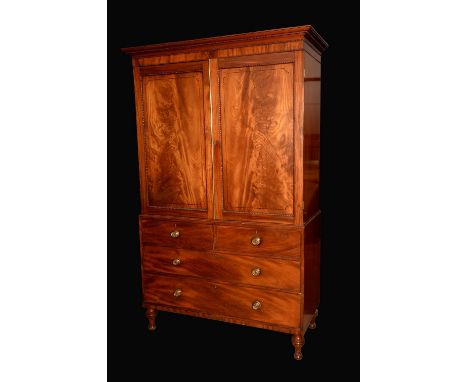 A well figured post-Regency mahogany linen press, outswept cornice above a pair of rectangular panel doors enclosing sliding 