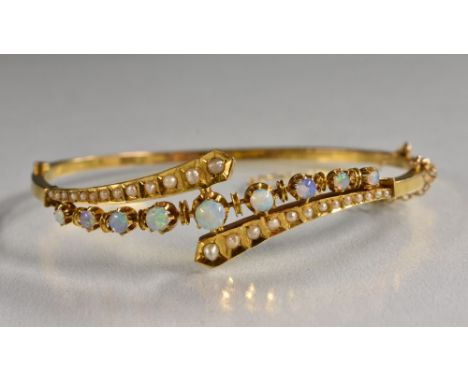 An opal and seed pearl hinge bangle, cross over pearl inset shoulders with central row of nine graduated round opals, flashin