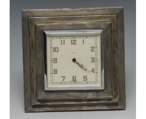 An Art Deco silver easel clock, with white enamelled dial with Arabic numerals, stepped engine turned case, 13cm wide, Birmin