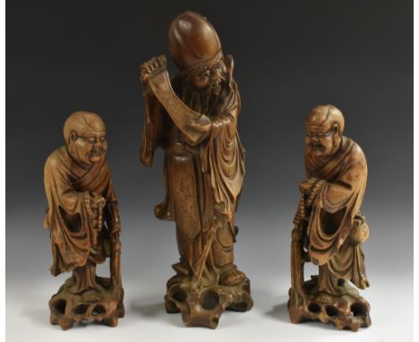 A pair of 19th century Chinese hardwood carvings, of Buddhistic sages, each robed and holding prayer beads, pierced outcrops,