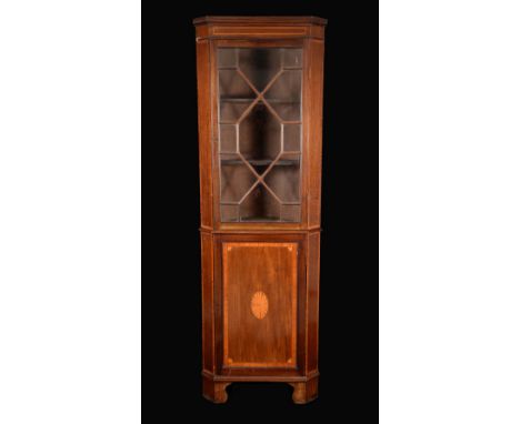 An Edwardian mahogany splay fronted floor standing corner display cabinet, moulded cornice above an astragal glazed door, the