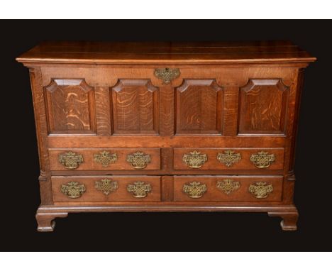 A George III oak mule chest, hinged top above a four panel front and four moulded drawers, pierced brass bat shaped handles, 