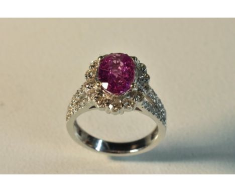 An oval pink sapphire and diamond cluster ring, central oval pink sapphire approx 9.5mm x 6.5mm x 4.2mm, surrounded by a band