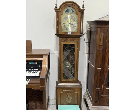 An oak longcase clock with break-arch dial and three train movement striking and chiming on twelve tubular gongs. Of recent m