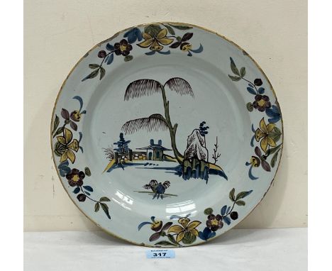An 18th century English Delftware plate polychrome decorated in Chinese style with a garden within a border of flowers. 12" d