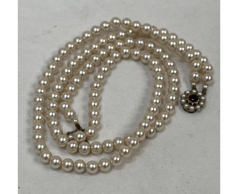 A double row pearl necklace, the 9ct clasp cluster set with a ruby and pearls. 14½" long