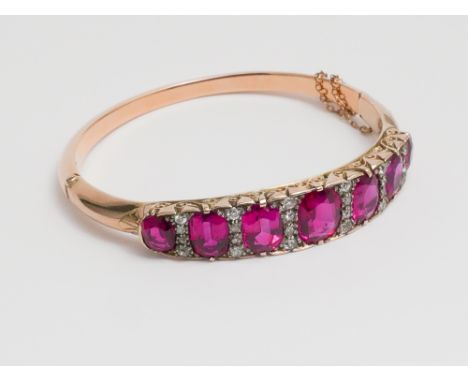 Victorian gold ruby and diamond set bangle set with 7 large oval synthetic rubies in a carved scrolled mount surrounded by di