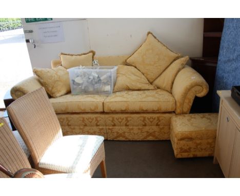 A gold floral upholstered three seater settee with matching pouffe