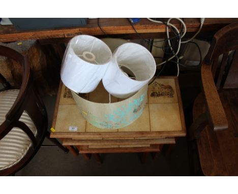 A nest of three tile top tables and three lamp shades