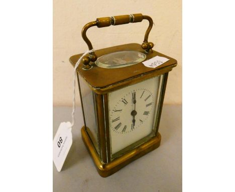 A brass cased manual wind carriage clock with white enameled dial and roman numerals. 