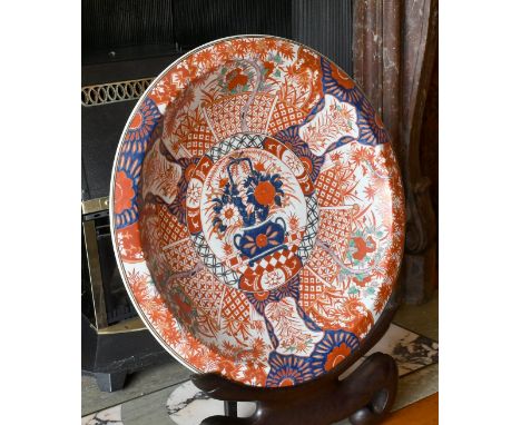 A LARGE JAPANESE IMARI DESIGN CIRCULAR CHARGER on a wooden stand. 2ft diameter.