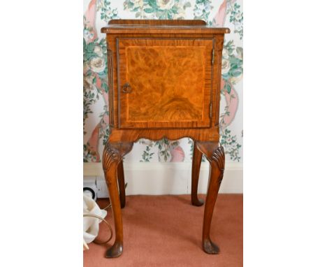 A FIGURED WALNUT BEDSIDE CUPBOARD with panel doors, on cabriole legs.