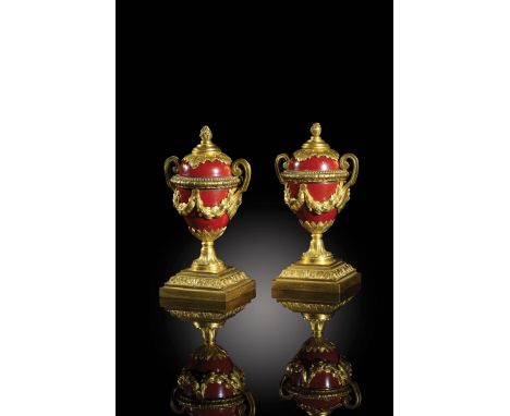 A pair of late 18th century ormolu cassolettes, each with a reversible bud finial, revealing a candle holder, to an ovoid red