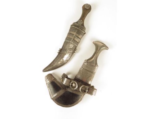 A Persian jambiyya, with a medial ridged curved blade and horn handle with silver coloured metal mounts in a leather and meta