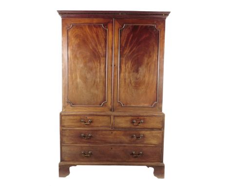 A George III mahogany linen press, with a detachable dentil cornice above a pair of doors with outline mouldings enclosing fi