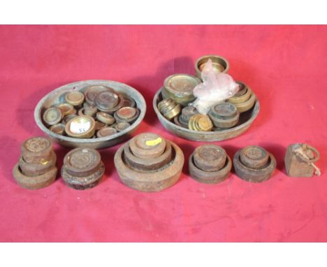 A pair of circular brass weighting scale pans and a large collection of various brass and iron weights