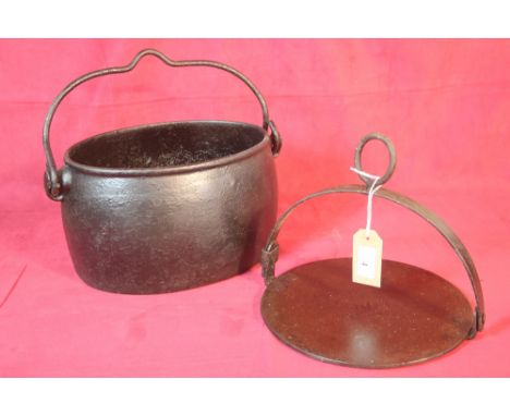 A cast iron oval swing handled cooking pot and an iron griddle