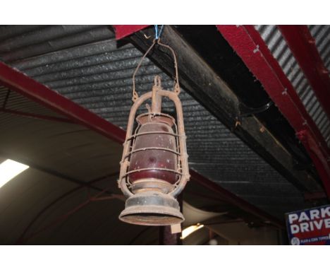 A hurricane lamp with ruby glass shade