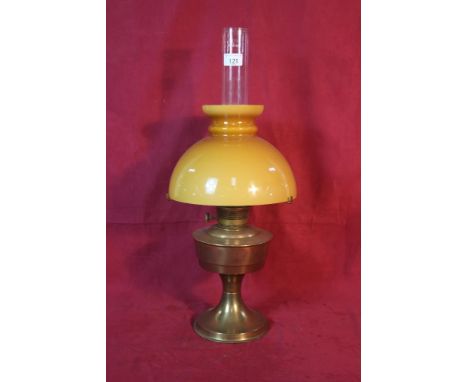 A brass oil lamp with amber coloured opaque glass shade
