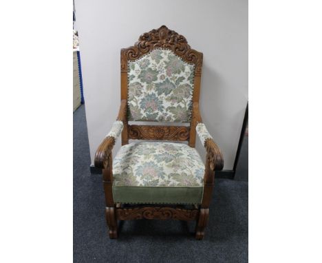 A heavily carved oak armchair with floral tapestry covering 