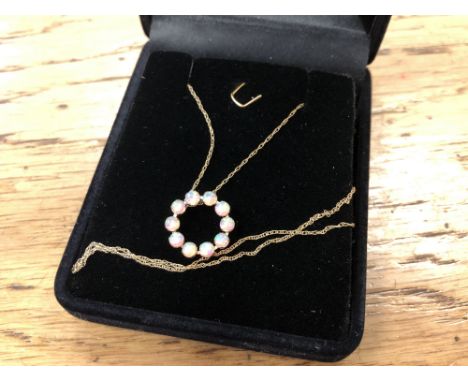 An opal circular pendant mounted in yellow gold on chain