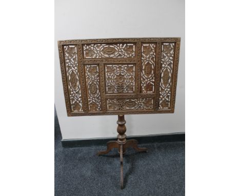 A carved fret work fire screen on tripod base 
