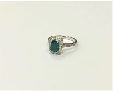 An 18ct white gold emerald and diamond cluster ring, size M1/2. CONDITION REPORT: 4.3g. 