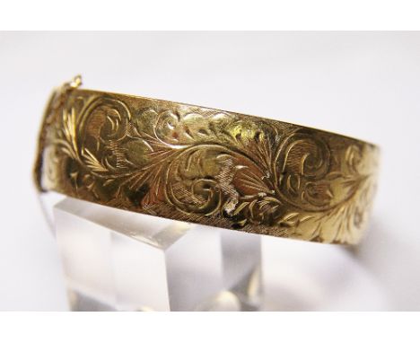 HINGED BANGLE. 9 ct gold front and back engraved hinged bangle