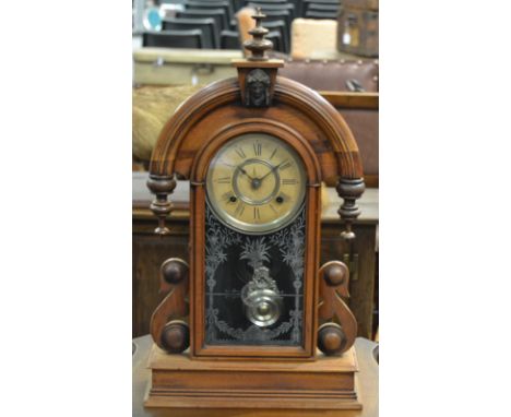 A Victorian walnut cased Ansonia mantle clock in arch case enclosed by a leaf patterned glazed door on a plinth base, height 