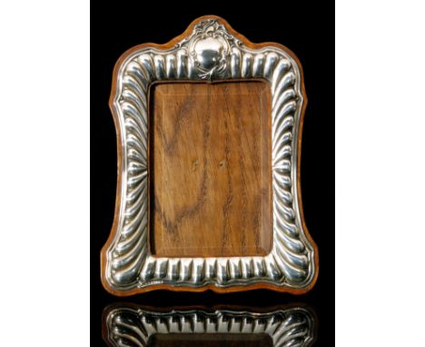 A late Victorian hallmarked silver mounted easel back photograph frame of shaped rectangular outline, the wooden mount with a