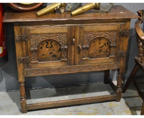 A 17th Century style oak cupboard enclosed by a pair of marquetry inlaid and arch panelled doors on turned legs united by rai