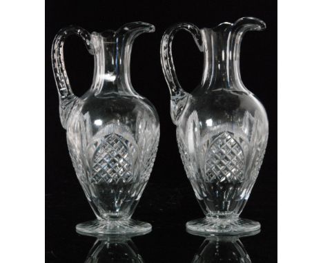 A pair of late 19th Century Stourbridge clear crystal water jugs of footed shouldered ovoid form with slice cut neck and appl
