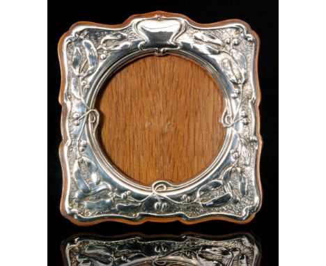 An Edwardian hallmarked silver mounted easel back photograph frame of shaped square outline, the wooden mount with embossed h