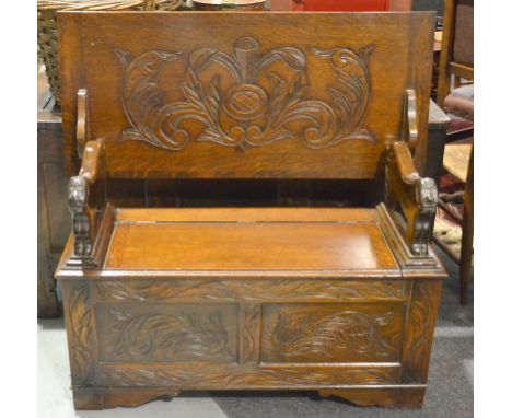 A 20th Century carved oak monks bench with lion shaped arm rests over a panelled front on bracket plinth, width 106cm