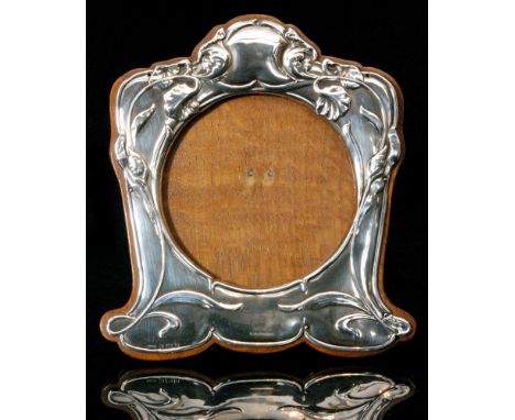 An Art Nouveau silver mounted easel back photograph frame of shaped rectangular outline, circular aperture decorated with sin