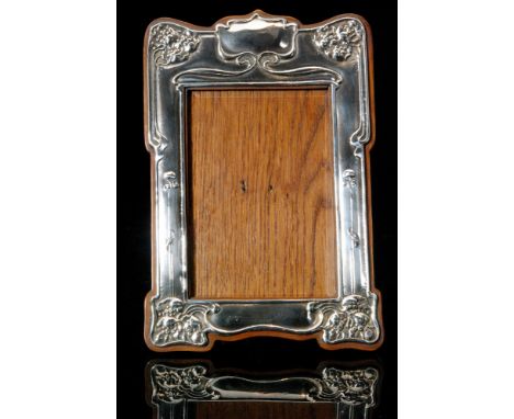 An Art Nouveau silver mounted easel back photograph frame of shaped rectangular outline decorated with sinuous foliate stems 