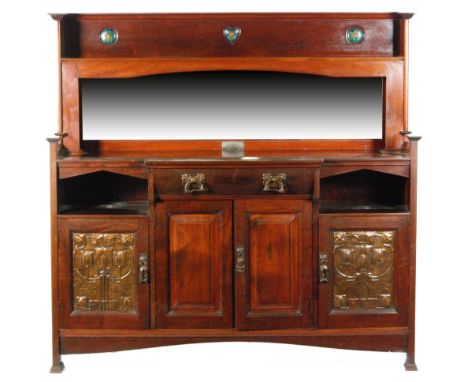An early 20th Century Arts and Crafts mahogany sideboard in the manner of Liberty & Co, the cornice pediment with enamelled r