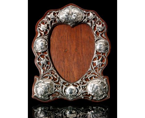 An Edwardian hallmarked silver mounted easel back shield shaped photograph frame decorated with five embossed panels, each de