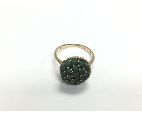 A gold ring set with green stones, approx 3g and approx size J-K. Shipping category A.