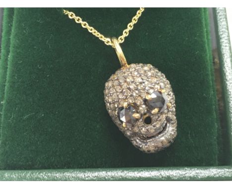Diamond set skull pendant with black diamond eyes, in silver and silver gilt, on a gold plated silver chain, boxed. Diamonds 