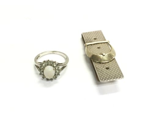 A silver ring set with opal silver U and a silver money clip.