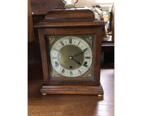 A mahogany mantle clock the dial with Roman numerals.