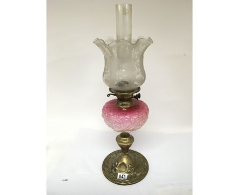 An Art nouveau glass and brass oil lamp with a pink glass reservoir and acid etched shade.